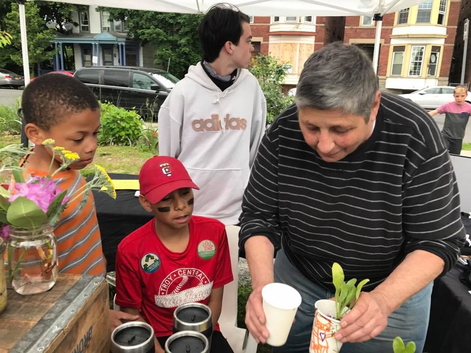 An older person is seen showing children how to care for plants