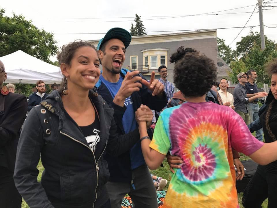 Two people smiling and talking as others are gathered around.