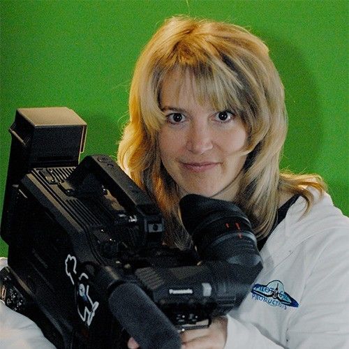 A headshot of Sonja Stark, holding a camera with a green screen behind her.