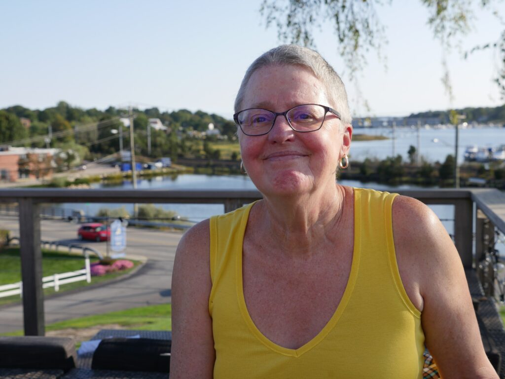 A headshot of Robin Oppenheimer, wearing a yellow tank top and smiling at the camera.