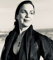 A headshot of Victoria Vesna in black and white, with her wearing a jacket with her hair pulled back looking into the distance.