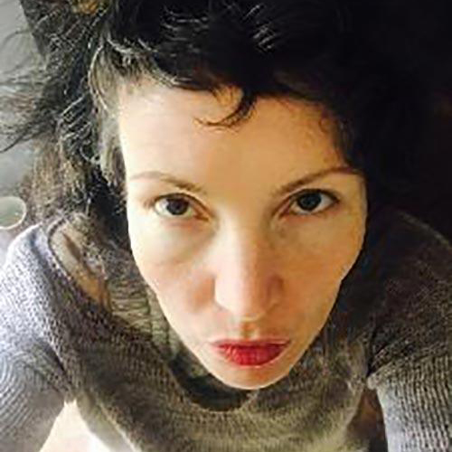 A selfie of Margaretha Haughwout: looking up into the camera with dark brown hair pinned to the side, wearing a great sweater. 