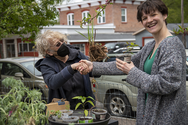 two people shaking hands as they exchange plants
