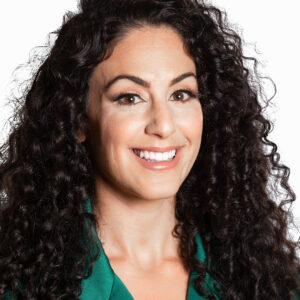 A headshot of Hades Alterman, who has long black curly hair and is wearing a green blouse.