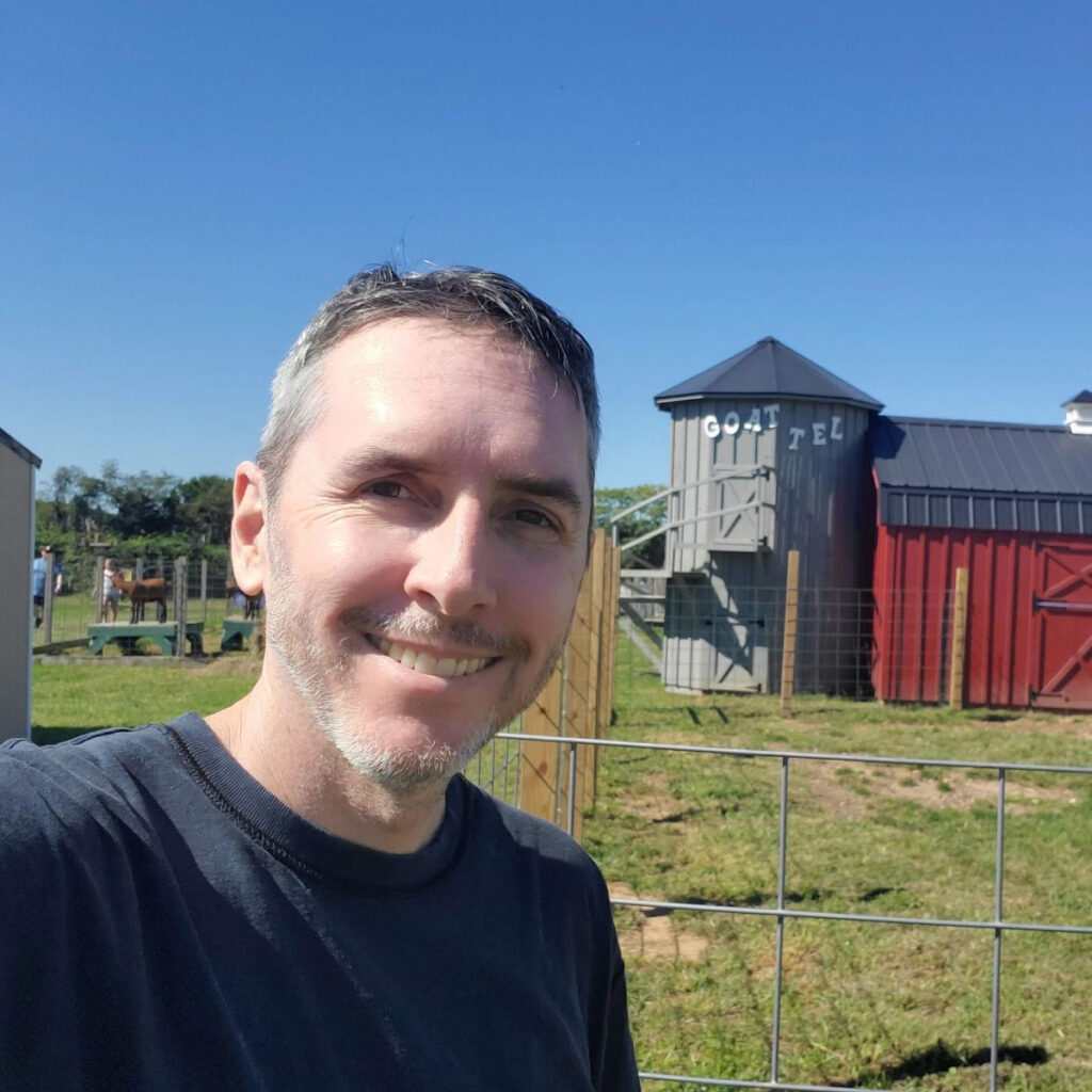 An image of Jim Walsh, posing in front of a farm.