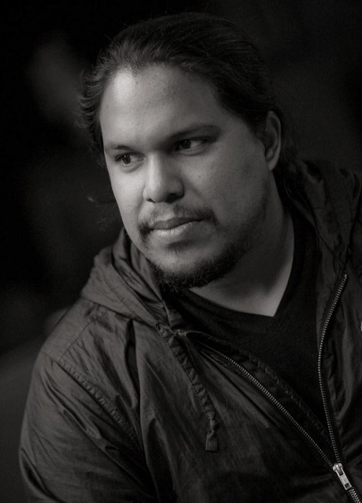 Headshot of Bryan Parras, looking off into the distance and wearing a grey hoodie and black shirt