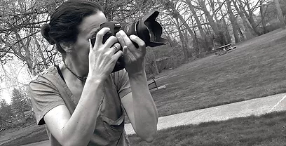Black and White picture of Jill Malouf holding camera in a park.