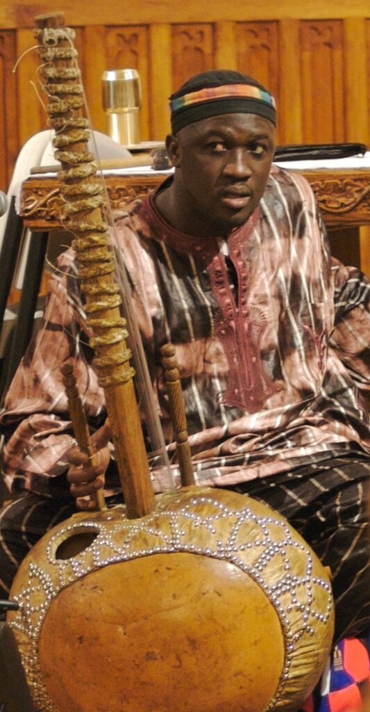 Mamadou Diabate sitting with a kora,   a stringed instrument used extensively in West Africa. Diabete is wearing traditional ethnic clothing. Photo by Johndan Johnson-Eilola.