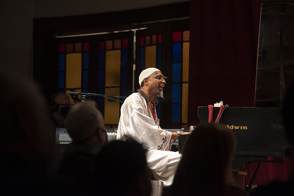 An action shot of Omar Sosa performing, playing the piano.