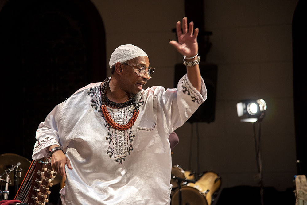 An action shot of Omar Sosa performing, playing the piano.