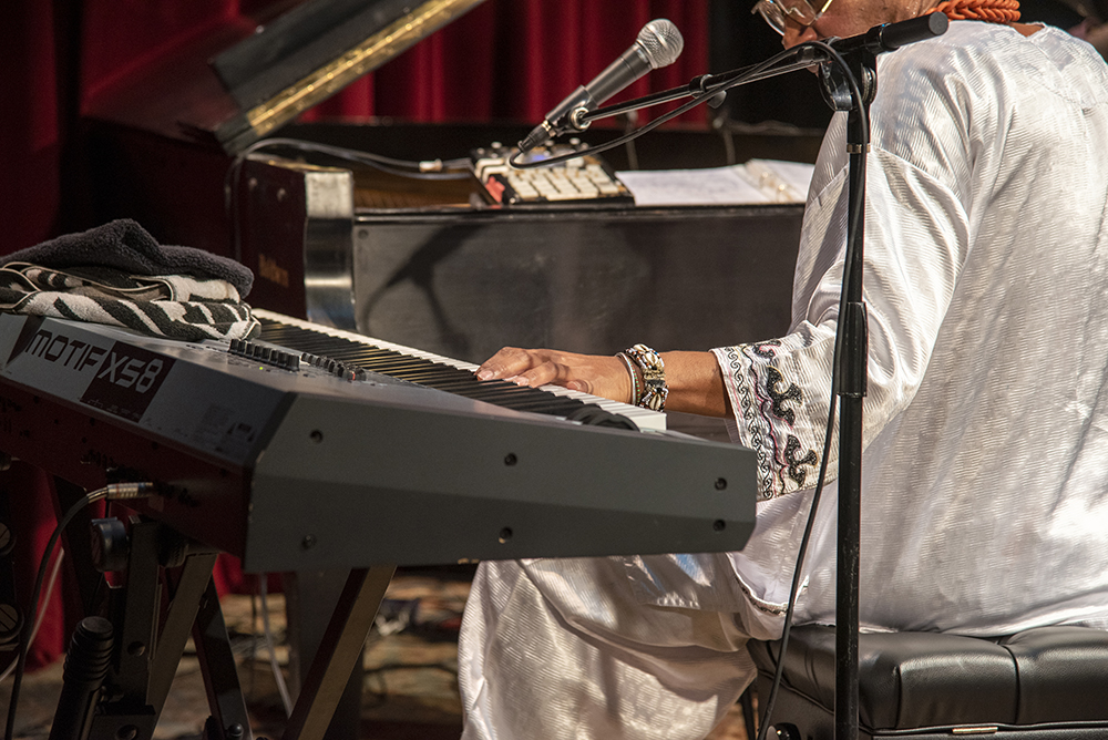 An action shot of Omar Sosa performing, playing the piano. (playing both electronic keyboard and piano)