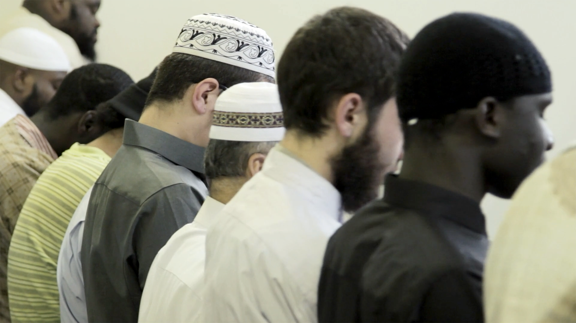 An image showing the back of several men, some wearing Omani caps.