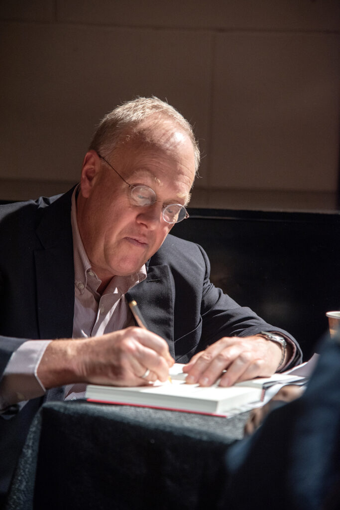 An image of Chris Hedges signing a copy of his book for an audience member.