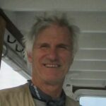 A white man with short grey hair smiles at the camera. 