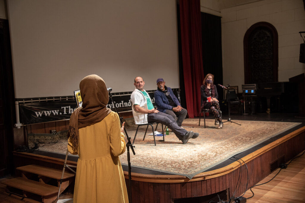 A woman with a headscarf talks to the three members of the presentation.