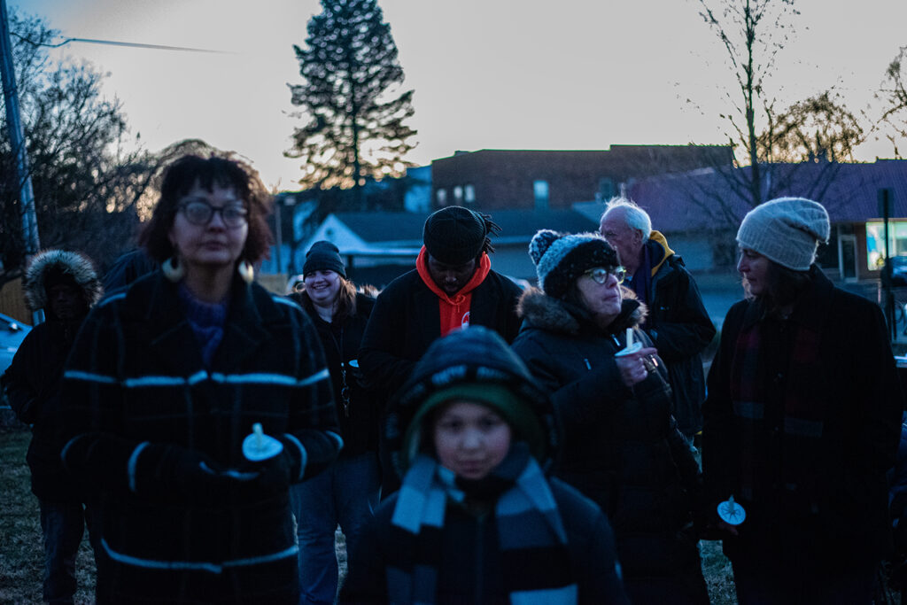 A group of people, all bundled up for the cold, gathered around holding candles preparing for the ceremony. 