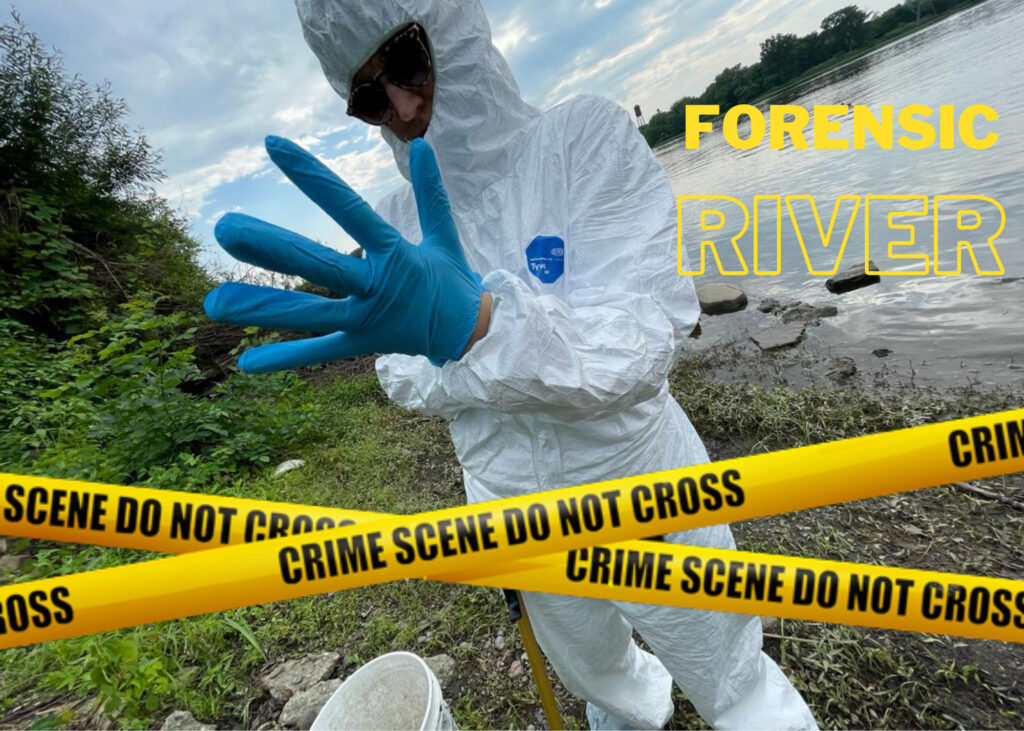 A person covered head to toe in a white hazmat suit, with blue rubber gloves and sunglasses, stands on the bank of a river. yellow hazard tape criss-crosses the image in front of them