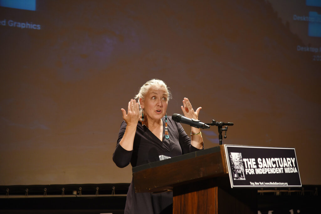 Kahstoserakwathe Paulette Moore on stage mid gesture with hands on either side of her face and a surprised expression