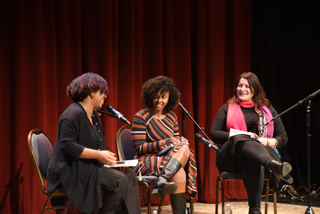 a photo of Jayana LaFountaine, Zoraida Lopez-Diago, and Lesly Deschler Canossi seated on stage at The Sanctuary for Independent Media, speaking into microphones.