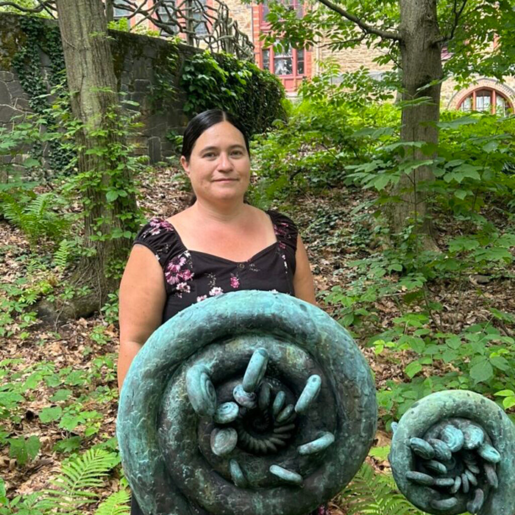 Misty Cook standing in front of a fiddlehead scuplture