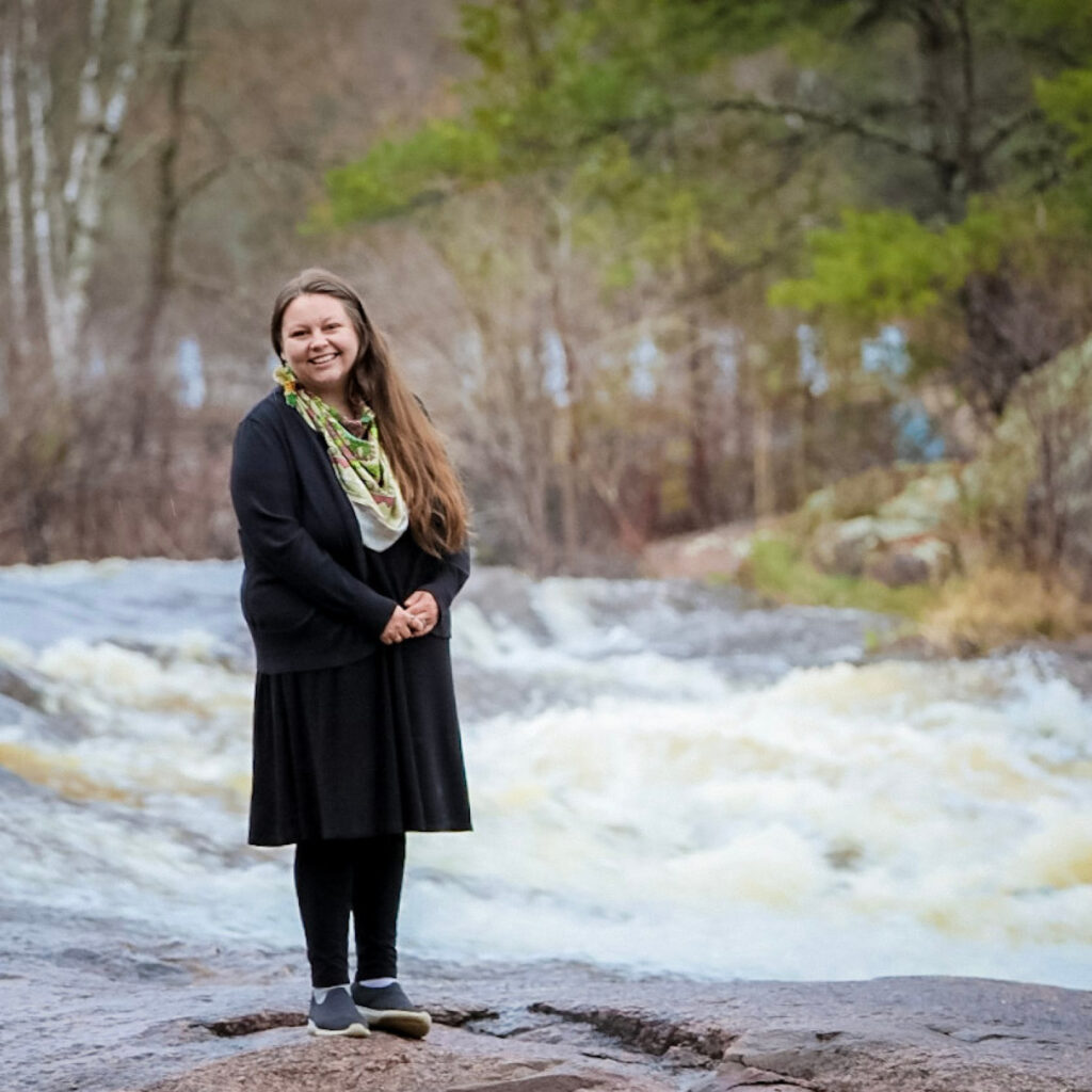 Lucille Burr Grignon standing in front of a rushing river