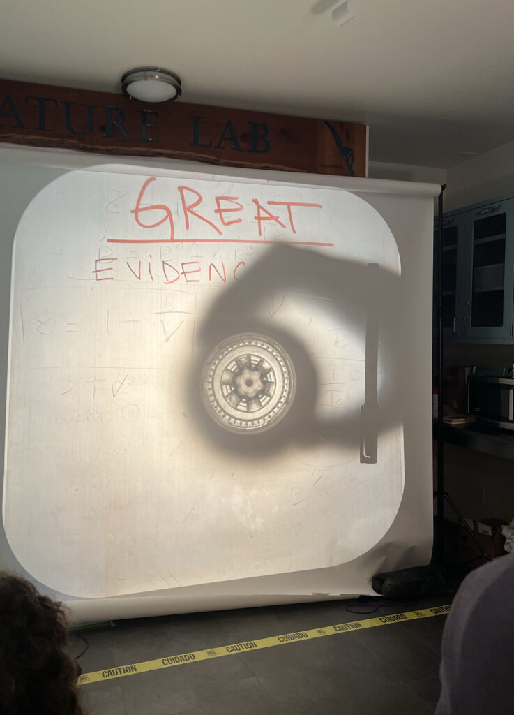 The handwritten words "GREAT EVIDENCE" are projected on a white screen. 