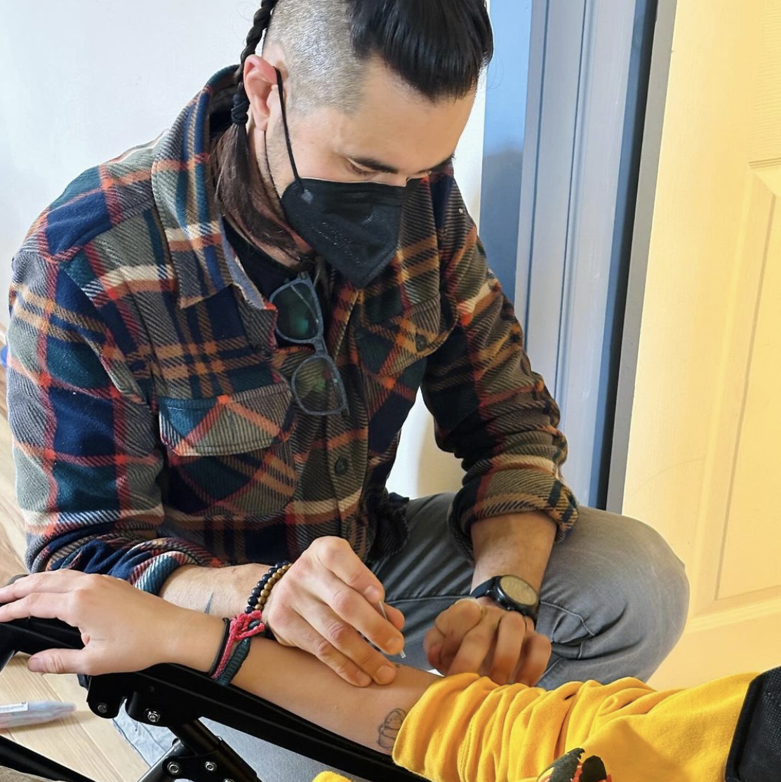 Dr Xavier Coughlin administers an acupuncture needle into a person's forearm