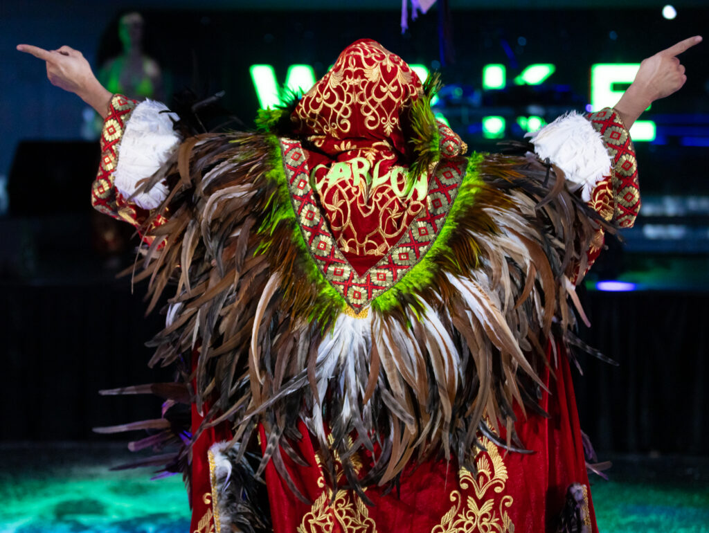 a person has their arms outstretched while wearing a cape of sorts that has feathers and embroidery 